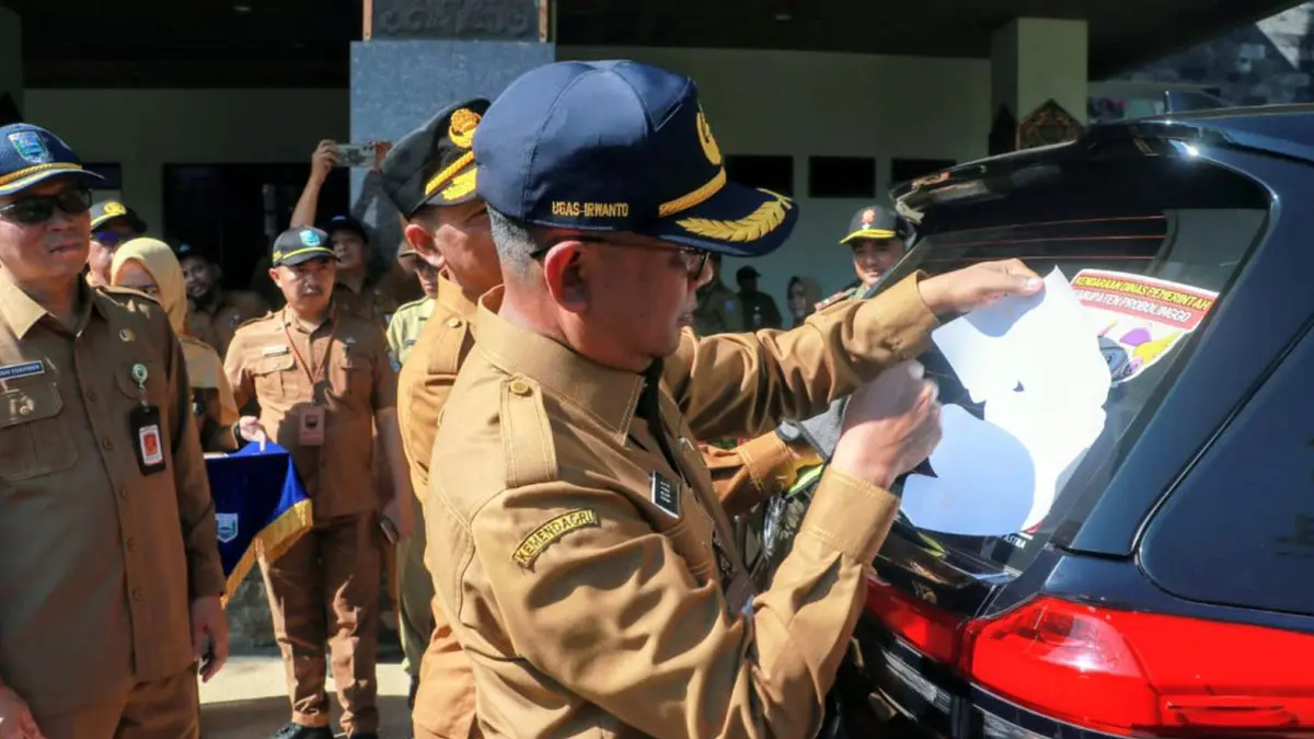 PASANG STIKER: Sekda Kabupaten Probolinggo Ugas Irwanto memasang stiker kepatuhan di salah satu mobil dinas, Senin (7/9).