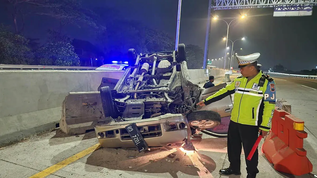 TERBALIK: Petugas kepolisian saat menunjukkan kendaraan korban yang terbalik di jalan tol usai menghantam beton barrier. (Unit Lantas Polsek Gempol for Radar Bromo)