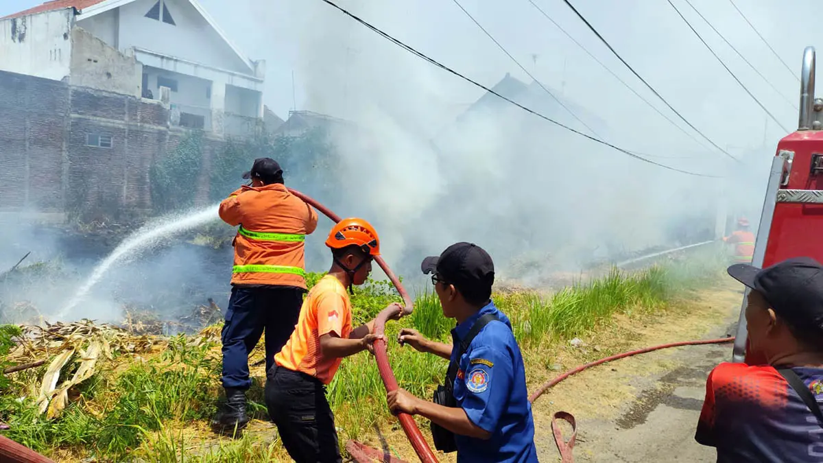 SIRAM: Petugas Damkar Kota Pasuruan saat berusaha memadamkan api yang membakar alang-alang. (BPBD Kota Pasuruan for Radar Bromo)