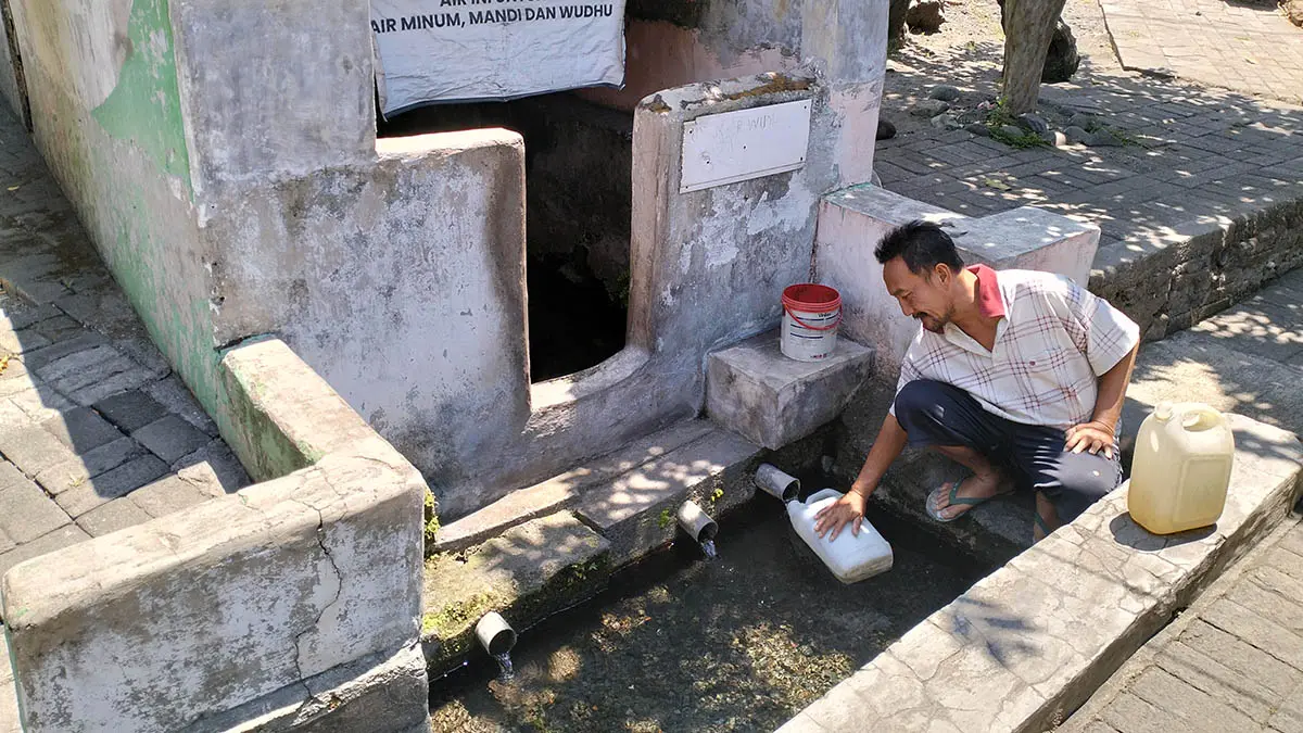 UNTUK OBAT: Seorang warga mengisi air dari Sumber Ringgit di Dusun Wunut, Desa Sumberejo, Kecamatan Pandaan. (Rizal Syatori/Radar Bromo)