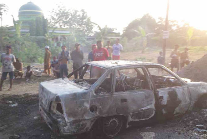 JADI TONTONAN: Mobil Daewoo milik Nasor yang gosong usai terbakar di Desa Tampung, Kamis (23/8) sore. (Polsek Lekok for Jawa Pos Radar Bromo)