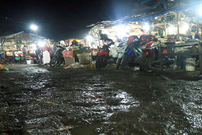 Akses utama jalan keluar masuk gerbang barat pasar Pandaan tampak dalam kondisi becek dan kotor, Kamis (15/6/2017) pagi. Minimnya sistem drainase ditambah rendahnya podasi jalan kerap membuat jalan terkesan kumuh saat hujan turun.