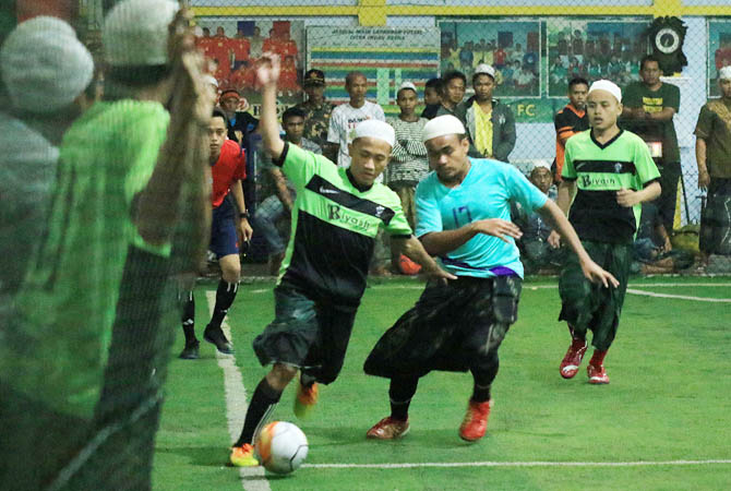 Tim Riyadusholihin Kota Probolinggo berebut bola dengan pemain tim Ponpes Bayt Al Hikmah Kota Pasuruan memperbutkan juara tiga di laga futsal sarungan antar santri, Jumat (17/11) malam.