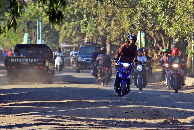 ALA OFFROAD: Seorang pengendara motor memacu motornya sambil berdiri saat melintas di Jalan KH Mas Mansyur yang kondisinya rusak penuh dengan lubang dan bergelombang.