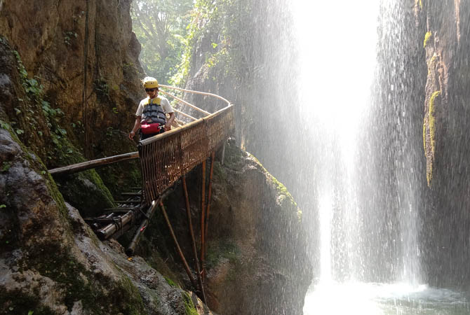 BERKEMBANG: Seorang pengunjung Air Terjun Purba Tirai Bidadari, Kecamatan Tiris, melintasi jembatan bambu yang disediakan pengelola. Disporaparbud masih terus memperhatikan pengembangan destinasi wisata, termasuk peningkatan kemampuan SDM-nya. (Foto: Achm