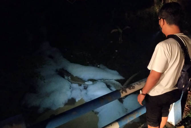 BERBUSA: Warga mengamati Kaliputih di Sumbersuko, Gempol yang tercemar busa, Selasa malam (27/10). (Rizal Syatori/ Radar Bromo)