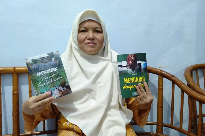 SEKARANG PENGAWAS: Jamilah menunjukkan dua buku yang dituliskan tentang kisah dan perjuangan guru. (Foto: Istimewa)