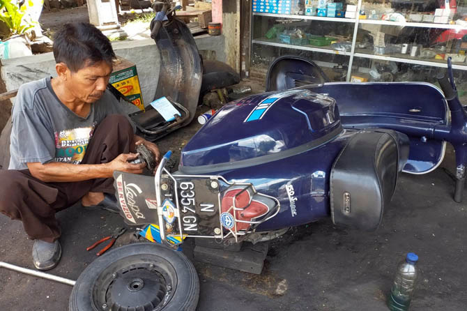 SUDAH DIKENAL: Kharisun saat membenahi skuter di bengkelnya. (Foto: Rizal F. Syatori/Jawa Pos Radar Bromo)