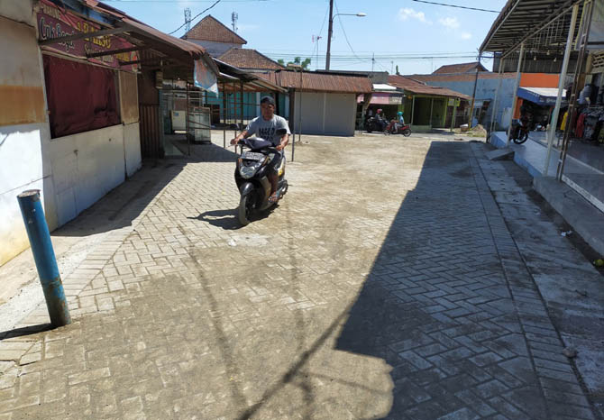 LEBIH BAIK: Pengendara motor melintas di jalan bagian dalam Pasar Senggol, Kelurahan/Kecamatan Pandaan, Kabupaten Pasuruan, yang sudah rampung dipaving. (Foto: Rizal Fahmi Syatori/Jawa Pos Radar Bromo)