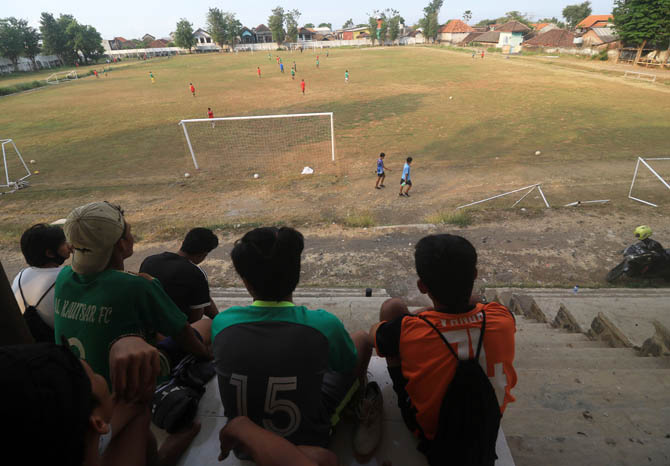 NONTON: Sejumlah warga menonton pertandingan lapangan sepakbola di lapangan Plumbon. Lapangan ini dan empat lapangan lainnya kini dikelola Dispora Kabupaten Pasuruan. (Foto: M Zubaidillah/Jawa Pos Radar Bromo)