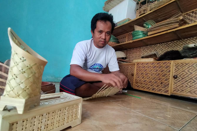 FOKUS LOKAL: Toyib mengerjakan anyaman bambu pesanan di rumahnya. Saat ini dia fokus memasarkan produknya di tingkat lokal. (Foto: Iwan Andrik/Jawa Pos Radar Bromo)