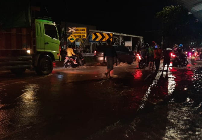 TERGENANG: Kendaraan yang melintas di Jalan Juanda tepatnya di bukwedi di Blandongan, harus pelan-pelan karena jalan tergenang air. (Foto: Fahrizal Firmani/Jawa Pos Radar Bromo)