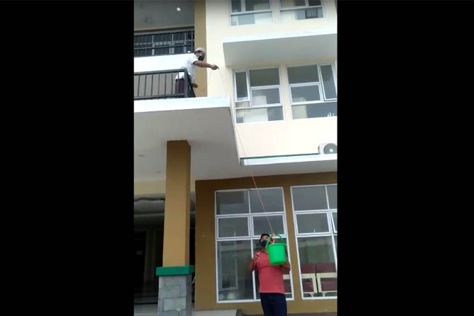 PAKAI TIMBA: Penulis saat mendapat kiriman makanan dan barang-barang di Rusunawa Mayangan yang jadi tempat isolasi pasien covid. (Foto: Istimewa)