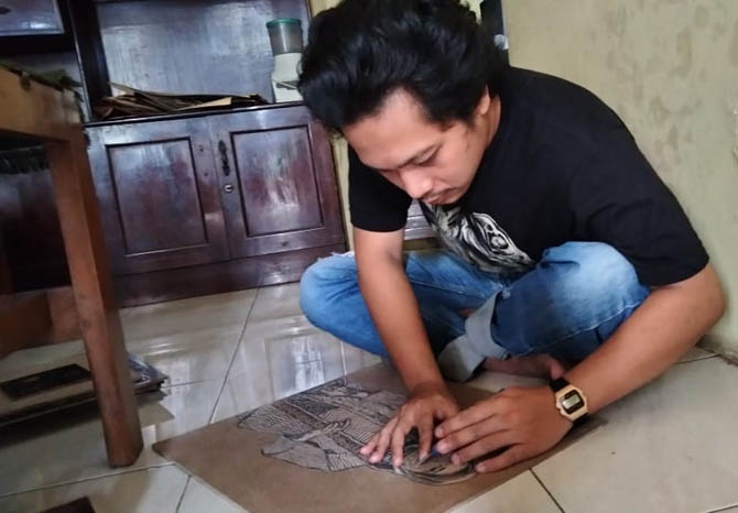 LEBIH MUDAH: Mauludi Achmad saat mencukil sketsa wajah pesanan seorang konsumen. Kini, lebih mudah baginya menggambar sketsa wajah karena menggunakan aplikasi. (Foto M Busthomi/Jawa Pos Radar Bromo)