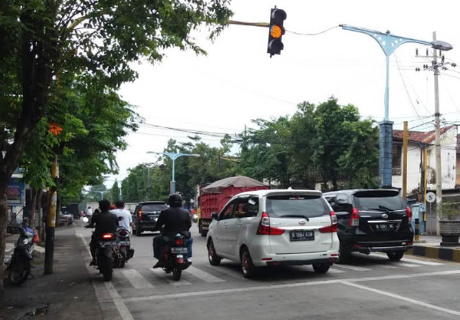 SUDAH NORMAL: Pengendara yang meintas di Jalan Panglima Sudirman Kraksaan, Selasa (9/2) siang. Nampak traffic light di lokasi ini sudah mnyala normal. (Foto: Achmad Arianto/Jawa Pos Radar Bromo)