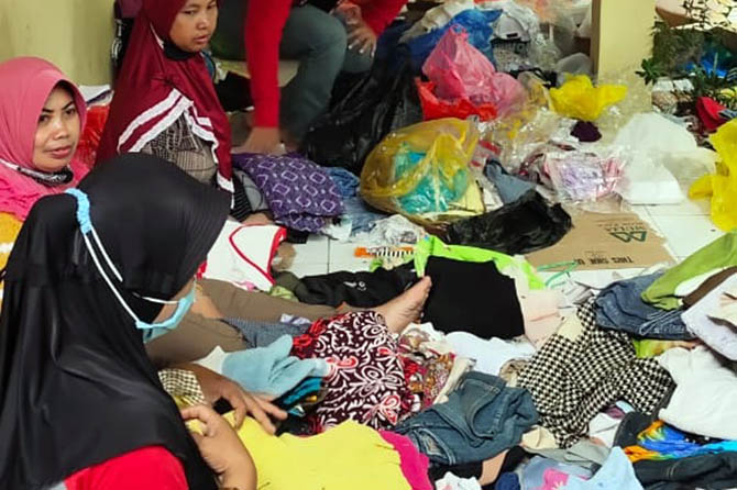 DISORTIR: Tidak hanya sembako, bantuan berupa pakaian layak pakai terus berdatangan ke posko Kabupaten Probolinggo di kantor Kecamatan Dringu. Petugas pun menyortir baju layak pakai sebelum disalurkan pada ribuan korban banjir, Jumat (12/3). (Arif Mashudi