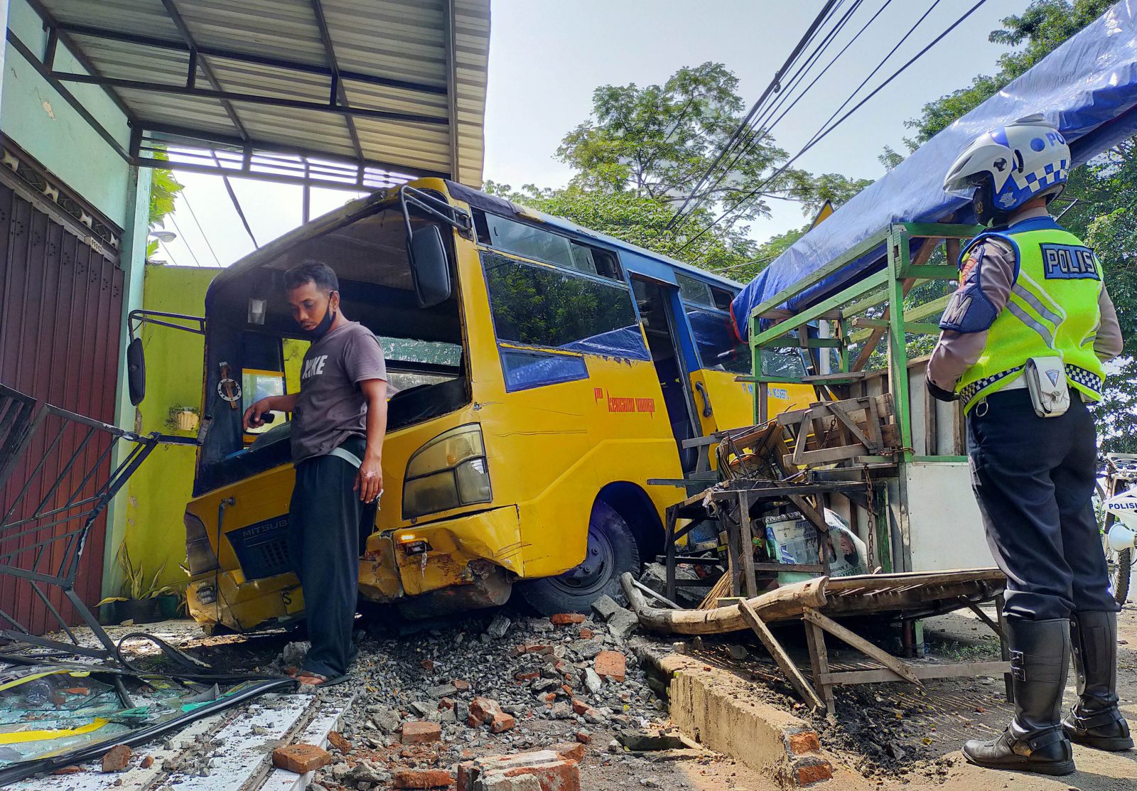 APES: Bus kuning yang menabrak pagar rumah di Desa Beji, Minggu (7/3) pagi. (Foto: Iwan Andrik/Jawa Pos Radar Bromo)