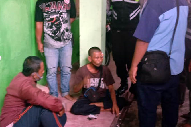 BAKAL DIBAWA KE RSJ: Basori (duduk, tengah) saat diamankan warga usai membacok tetangganya. (Dok. Radar Bromo)