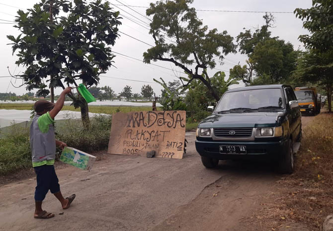 ANDALKAN PENGENDARA: Pengendara yang melintas di Jalan Desa Ngepoh di pagi hari. Nampak ada warga sekitar yang mencari sumbangan, dan dana tersebut digunakan untuk perbaikan jalan rusak. (Foto: Arif Mashudi/Jawa Pos Radar Bromo)