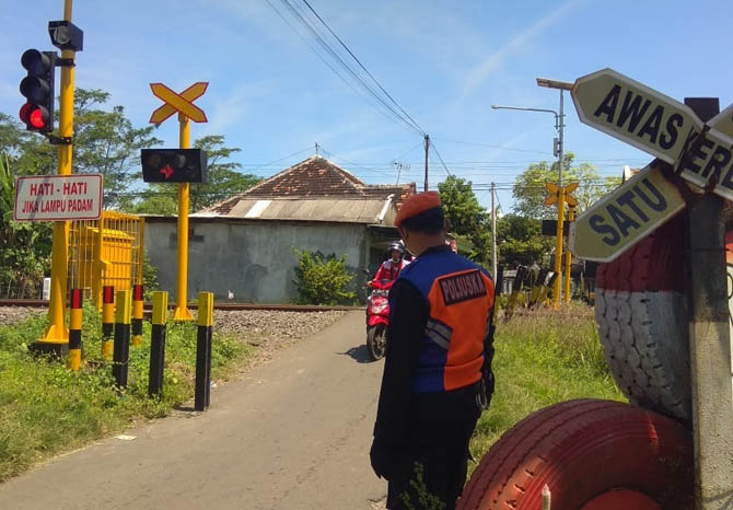 TANPA PALANG: Personel Polsuska standby di perlintasan KA di Jalan Sunan Muria, yang Jumat (16/4) siang sirinenya berbunyi terus. (Foto: Rizky Putra Dinasti/Jawa Pos Radar Bromo)