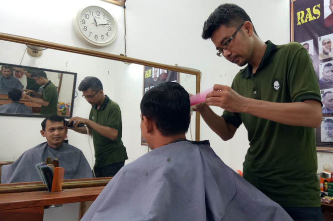 RAPIKAN RAMBUT: Ariyan, tukang potong di pasar Kebonagung, mencukur pelanggannya, Rabu (31/3) siang. (Foto: Mukhamad Rosyidi/Jawa Pos Radar Bromo)