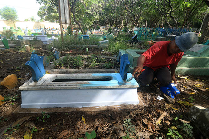 BIAR TERLIHAT: Seorang pengunjung mengecat makam kerabatnya di TPU Purutrejo II. Menjelang Idul Fitri, banyak warga yang membersihkan makam. (Foto: M Zubaidillah/Jawa Pos Radar Bromo)