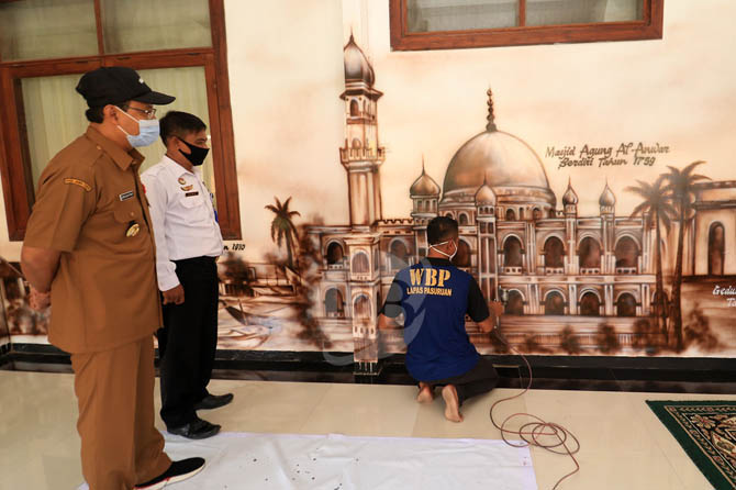 WARGA BINAAN: Eddy saat melukis mural di pendapa Surga Surgi. Nampak Wali Kota Pasuruan Siafullah Yusuf melihat dia melukis. (Foto: M Zubaidillah/Jawa Pos Radar Bromo)