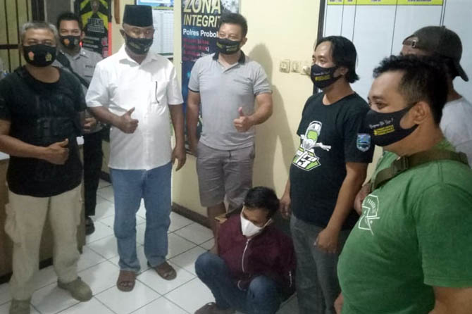 DIBEKUK: Kapolsek Kuripan AKP Kusmidi (berpeci) menunjukkan pelaku Yolan (jongkok) yang berhasil ditangkap selang 6 jam usai lakukan pembacokan. (Polsek Kuripan for Jawa Pos Radar Bromo)