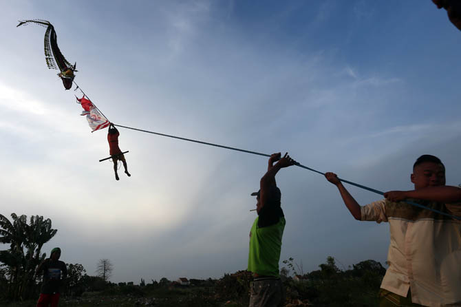 BERBAHAYA: Aditia Rifky naik layangan naga yang diterbangkan ayahnya Abdul Qodir. (Zainal Arifin/Jawa Pos Radar Bromo)