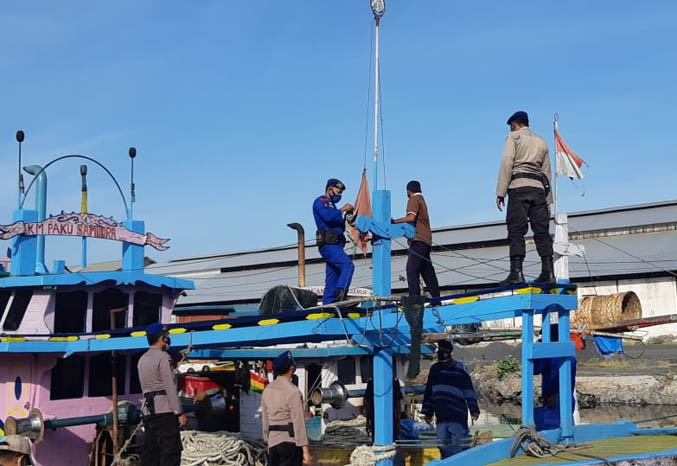 SIMBOL NEGARA: Personel Satpolair Polres Probolinggo mengganti bendera di salah satu kapal milik nelayan Probolinggo, Jumat (6/8). (Foto: Arif Mashudi/Jawa Pos Radar Bromo)