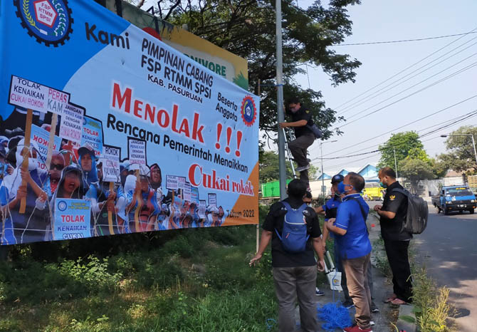 PROTES: Serikat pekerja memasang banner penolakan kenaikan cukai di bundaran Apolo, Gempol, Kamis (26/8).  (Foto: Rizal F Syatori/Jawa Pos Radar Bromo)