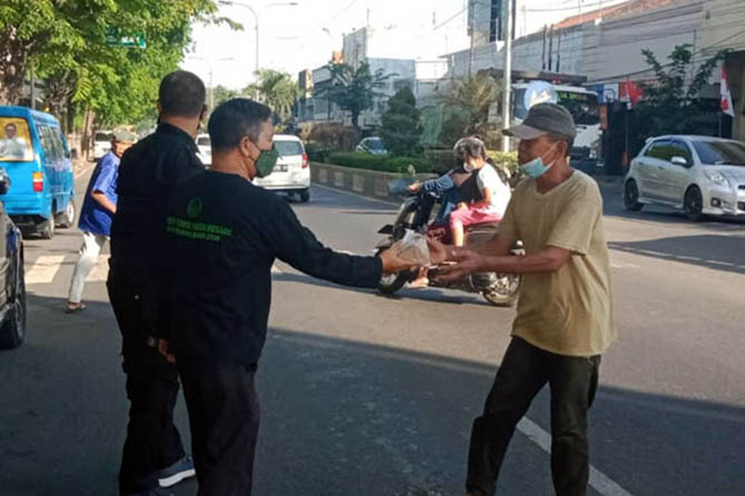 PEDULI: Pegawai Pemkot Pasuruan berbagi makanan dan sembako di Jalan Soekarno Hatta, Jumat (13/8). (Foto M. Busthomi/Jawa Pos Radar Bromo)