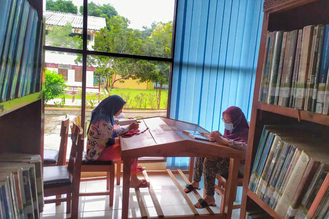 TAMBAH LITERASI: Dua pengunjung perpustakaan daerah membaca buku. Sampai kini pemkab belum membuka perpustakaan daerah karena butuh koordinasi dengan pihak terkait. (Foto: Dok. Radar Bromo)