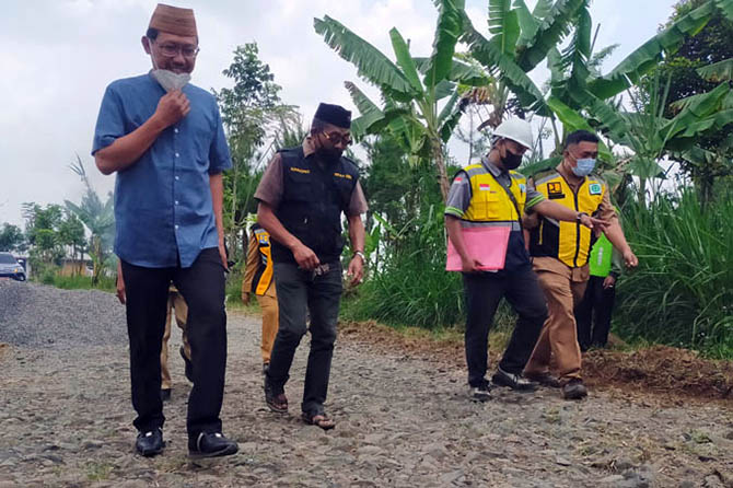 PENUHI HARAPAN: Ketua DPRD Sudiono Fauzan berjalan di atas makadam dan melihat perbaikan Jalan Desa Kalipucang dan Andonosari, Kecamatan Puspo, Senin (27/0) siang. (Foto: Iwan Andrik/Jawa Pos Radar Bromo)
