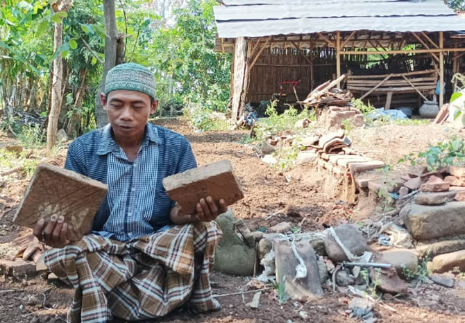 LIHAT: Anwar sedang memperlihatkan bata yang berbeda dengan bata biasanya. Bata tersebut sisa dari candi yang urung dibangun oleh putri. (Foto: Agus Faiz Musleh/Jawa Pos Radar Bromo)