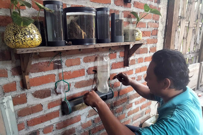 KREATIF: Zainul Afandi dan aquascape kreasinya yang terbuat dari bekas kaleng cat. (Muhamad Busthomi/Radar Bromo)