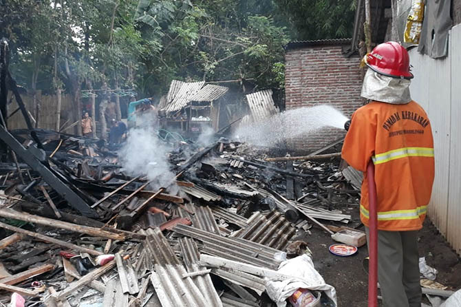 HANGUS: Tim Pemadam Kebakaran Kabupaten Probolinggo, menyiram titik api yang melalap rumah Sidik, warga Desa Sidodadi, Kecamatan Paiton, Sabtu (30/10). (Istimewa)