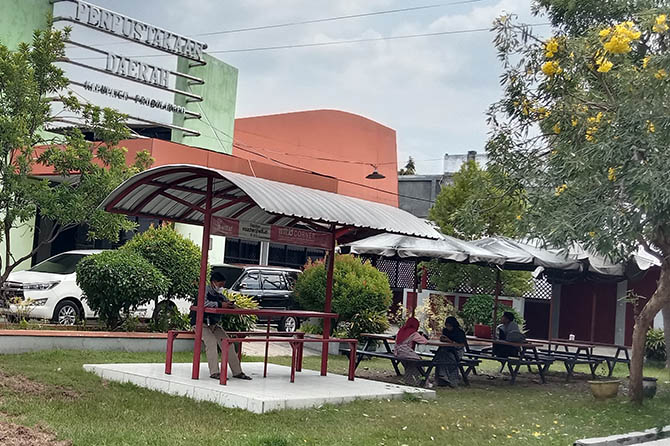 TAMBAH ILMU: Sejumlah pengunjung Perpustakaan Daerah Kabupaten Probolinggo, menikmati bacaannya di depan perpustakaan, beberapa waktu lalu. (Dok. Radar Bromo)