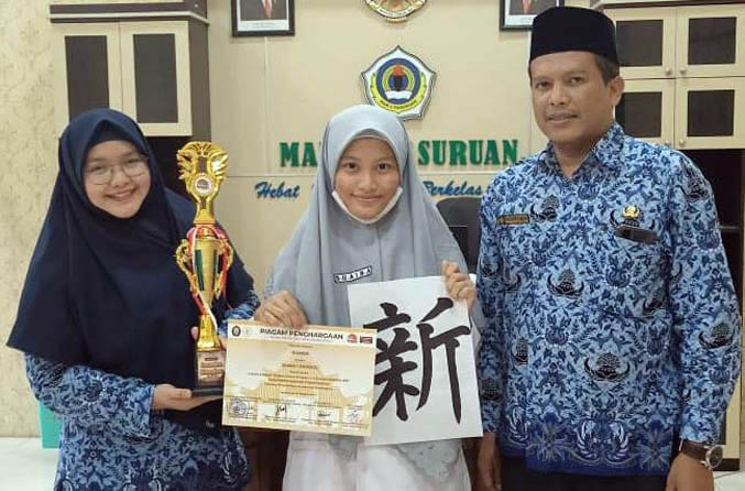 MEMBANGGAKAN: Suaiba (tengah) didampingi Kepala MAN 1 Pasuruan, Bustanul Arifin dan Fauziah, guru Bahasa Jepang MAN 1 Pasuruan. Dia menunjukkan senigrafi Jepang karyanya yang memenangi lomba tingkat nasional. (Foto: Iwan Andrik/Jawa Pos Radar Bromo)