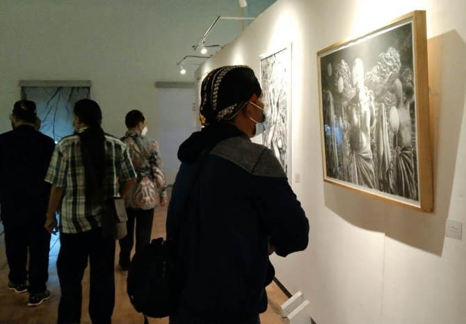 MENIKMATI KARYA SENI: Pengunjung melihat lukisan di pameran seni rupa yang digelar di kampus Uniwara Pasuruan, Sabtu (13/11) sore. (Foto M Busthomi/Jawa Pos Radar Bromo)
