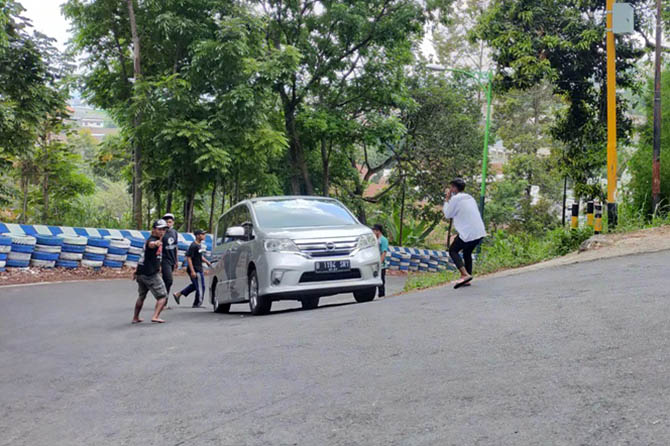 MOGOK: Beberapa supeltas mendorong sebuah mobil yang tidak kuat melaju di jalur tanjakan Jurang Ampel, salah satu jalur tengkorak di Kabupaten Pasuruan. (Foto: Rizal F. Syatori/Radar Bromo)