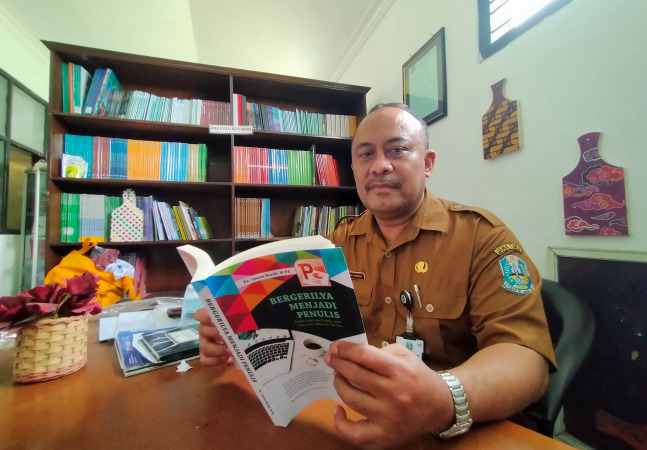 PRODUKTIF: Dr. H. Imron Rosidi menunjukkan salah satu buku karyanya. Saat ini, sekitar 26 buku umum nonfiksi karyanya yang sudah terbit. (Foto: Iwan Andrik/Jawa Pos Radar Bromo)