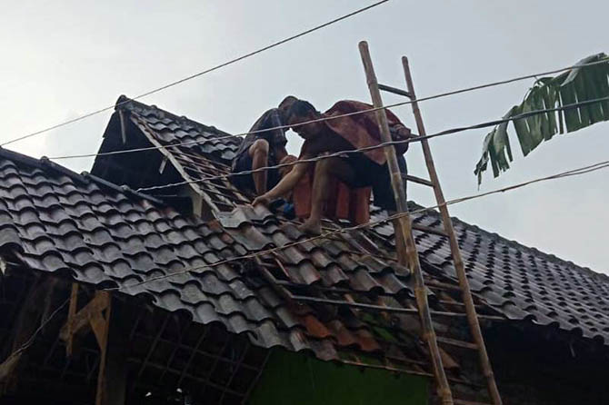 PERBAIKI ATAP: Warga memperbaiki atapnya yang rusak usai disapu puting beliung. (Istimewa)