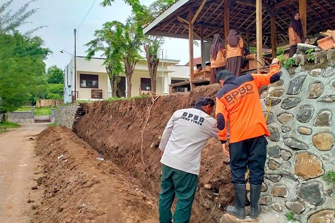 AMBROL: Petugas dari BPBD Kabupaten Probolinggo mengecek TPT di Desa Patemon, Kecamatan Krejengan, yang ambrol saat hujan deras, Jumat (14/1). (BPBD for Radar Bromo)