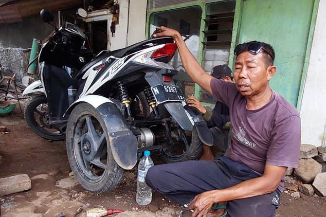 Irul tengah memperbaiki motor roda tiga salah satu konsumenya. (Foto: Rizky Putra Dinasti/Jawa os Radar Bromo)