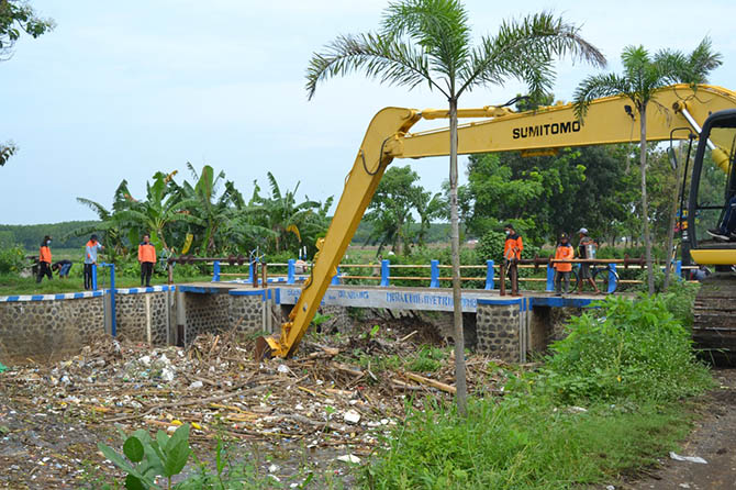 DIBERSIHKAN: Sejumlah petugas memantau pembersihan dam sungai muara Pantai Permata, Kelurahan Pilang, Kecamatan Kademangan. Ada sekitar 12 truk sampah yang menyumbat aliran sungai ini. (Zainal Arifin/Jawa Pos Radar Bromo)