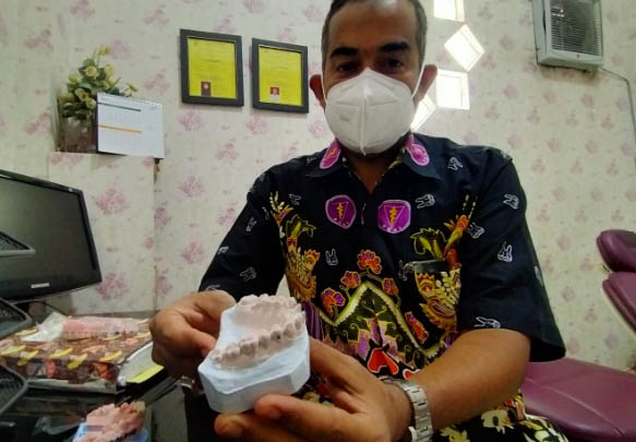 DIPERCAYA REKAN SEJAWAT: Drg Hafid Bauzir dan produk gigi tiruan buatannya. (Foto: Iwan Andrik/Jawa Pos Radar Bromo)