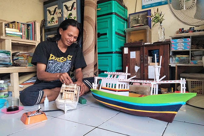 MINIATUR: Mustofa, 39, membuat miniatur perahu semirip mungkin dengan aslinya. Profesinya yang juga sebagai nelayan membuat dia hafal bagian detail perahu. (Foto: M. Busthomi/Jawa Pos Radar Bromo)