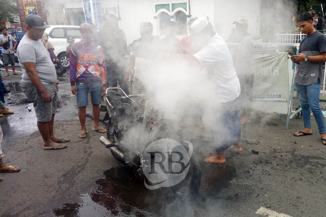Waarga saat berupaya memadamkan motor yang terbakar di ruas jalan depan Alun-alun Pasuruan, Senin (14/2). (Mukhammad Rosyidi/ Radar Bromo)