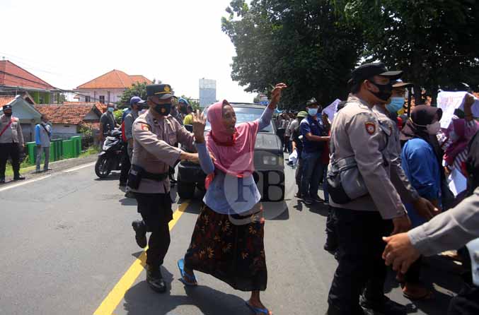 MASIH KERABAT CAKADES: Sakdiyah, warga Desa Pajurangan, Kecamatan Gending, dihalau polisi, Dia merupakan nenek dari Nanik Sri, Cakades Pajurangan yang kalah dalam pilkades. Sakdiyah juga ikut-ikutan demo sambil membawa poster, namun ia mulai memegang kepa